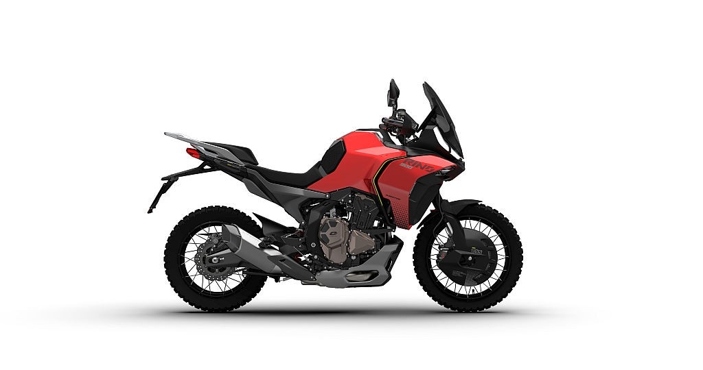 <div class='descrGalleryTitle'>QJ Motor Rino 900</div><div class='descrGalleryText'><p><b>QJ Motor</b>&nbsp;(padiglione 9, stand N54) alza l’asticella e presenta la <b>Rino 900</b>, crossover stradale che segna il debutto del marchio nel segmento delle maxi di media cilindrata. Il motore è un tre cilindri in linea da 120 CV, 12 valvole e distribuzione DOHC: numeri che la collocano tra le alternative più concrete alle proposte europee e giapponesi. Peso dichiarato: 220 kg con il pieno. Cerchio anteriore da 19” a raggi, scelta che conferma la vocazione più turistica che fuoristradistica.<br>
Il design porta la firma di <b>Adrian Morton</b>, già autore di diverse MV Agusta: frontale aggressivo, DRL a LED a “C” e un posteriore snello che alleggerisce la vista laterale. La ciclistica prevede telaio in tubi d’acciaio e forcellone in alluminio a doppio braccio con capriata inferiore. Non dichiarata la dotazione elettronica, ma la presenza del rinvio sul leveraggio cambio anticipa il quickshifter, probabile bidirezionale.<br>
Strumentazione TFT verticale da 7”, freni Brembo radiali, serbatoio da 20 litri. La produzione è vicina: QJ punta chiaramente al mercato europeo, non più solo come outsider, ma come alternativa credibile.</p>
</div>